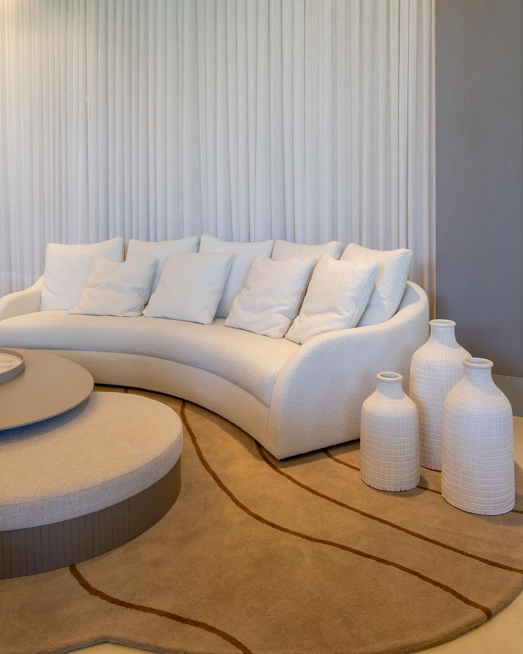 Cortinas brancas plissadas em sala minimalista com sofá curvo