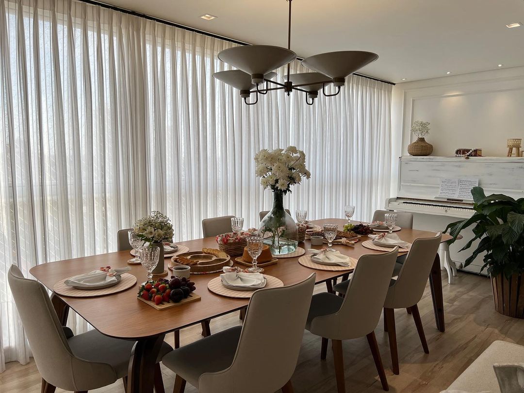 Cortinas brancas plissadas em sala de jantar com mesa decorada
