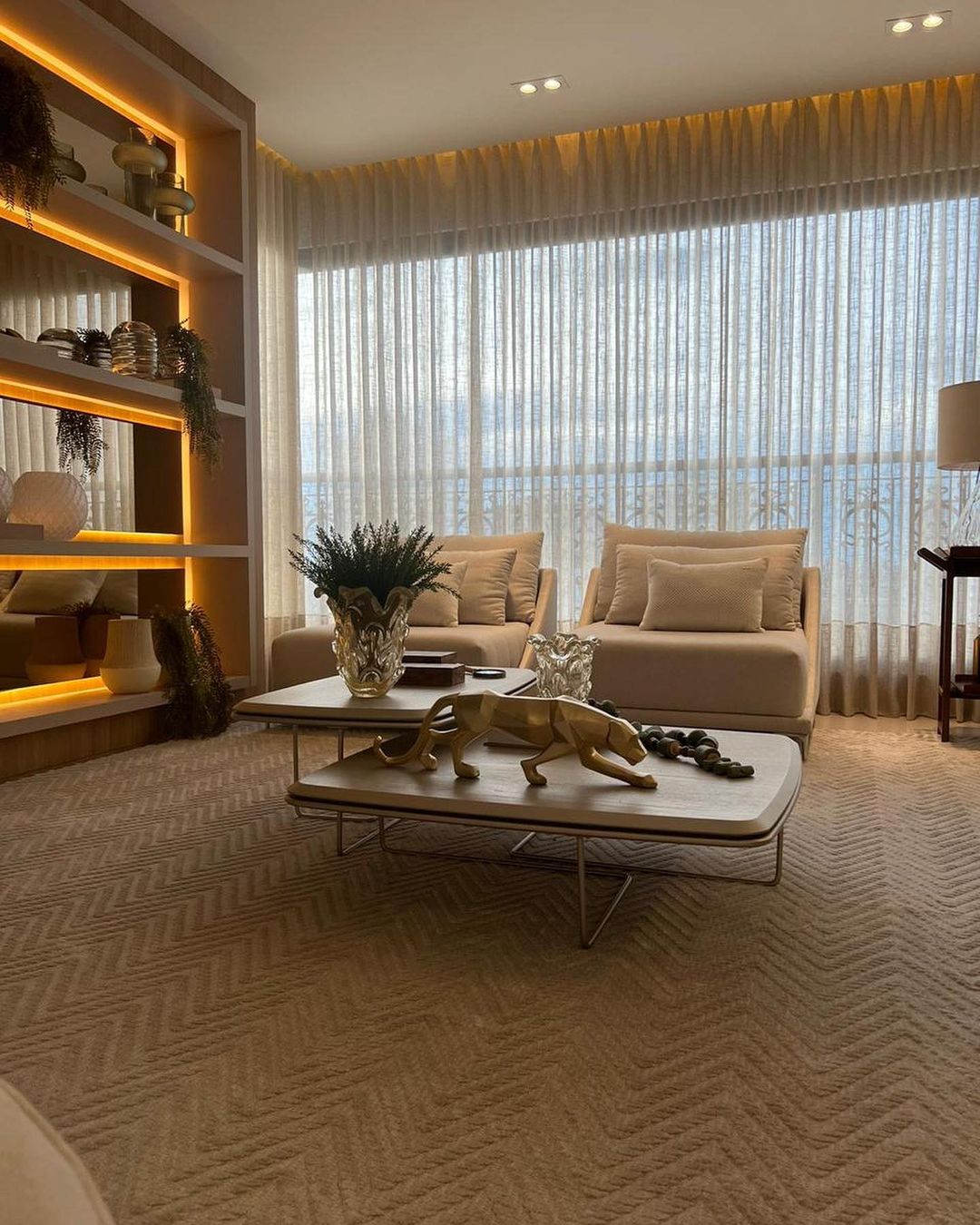 Cortinas brancas translúcidas em sala aconchegante com estante iluminada