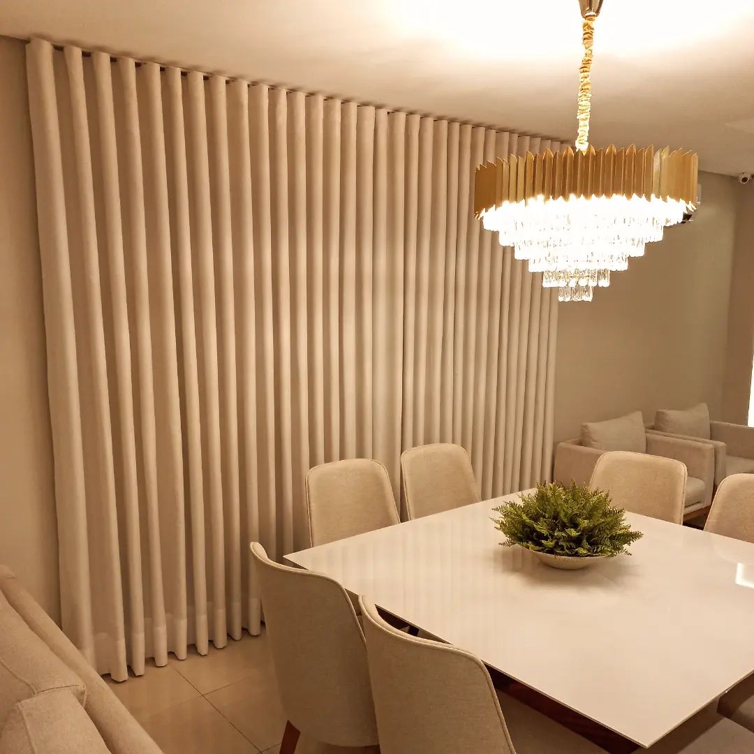 Cortinas bege em sala de jantar com lustre dourado