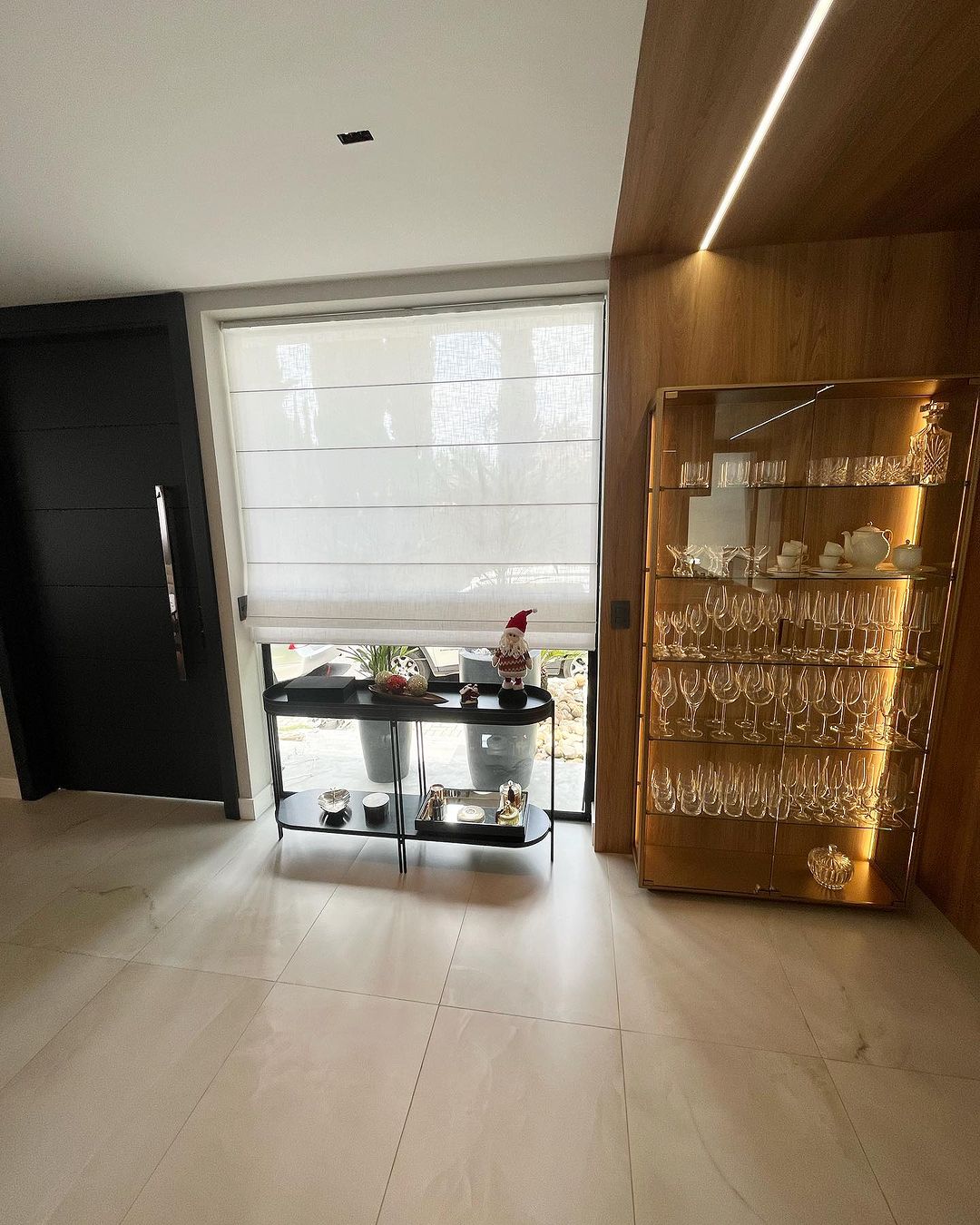 Persiana romana branca em hall de entrada elegante com cristaleira iluminada