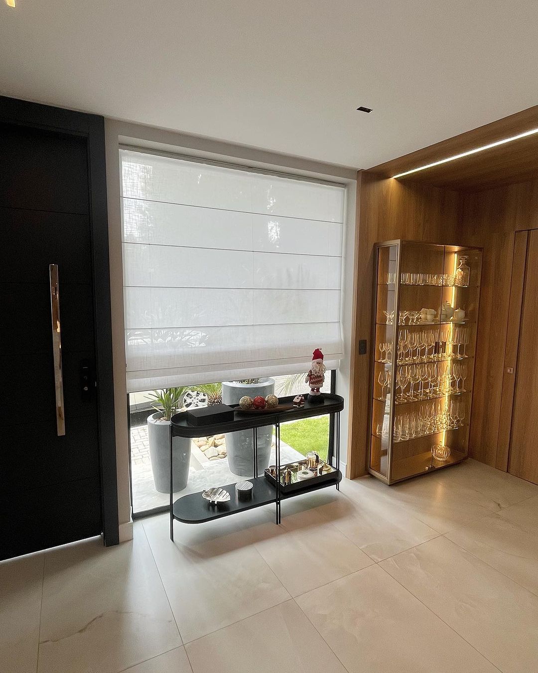 Persiana romana branca em entrada luxuosa com cristaleira de taças