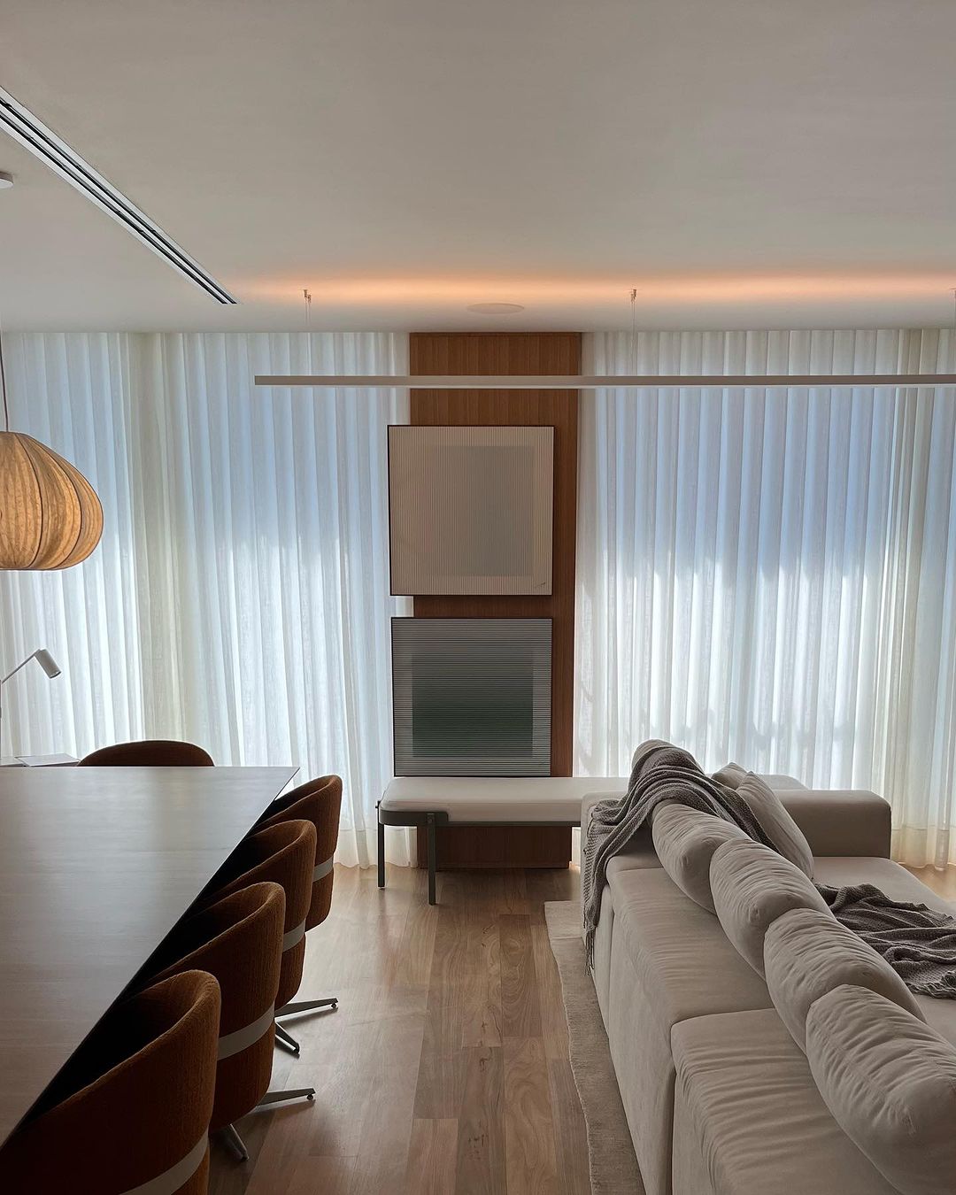 Cortinas brancas em sala integrada com painel de TV