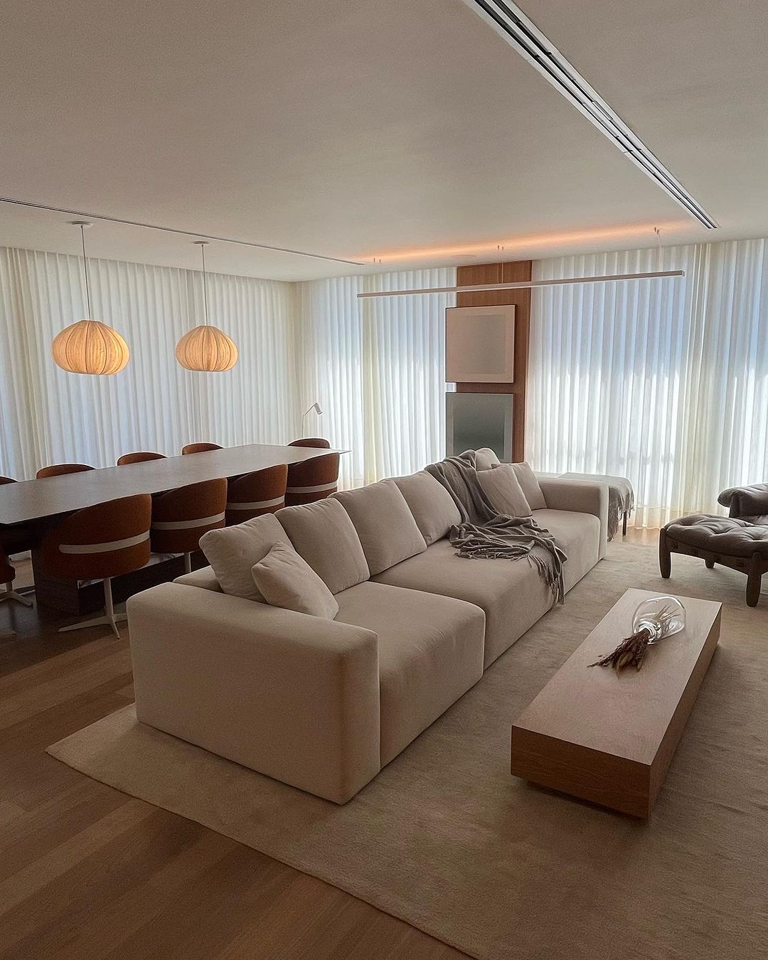 Cortinas brancas em sala ampla com lustres pendentes de madeira