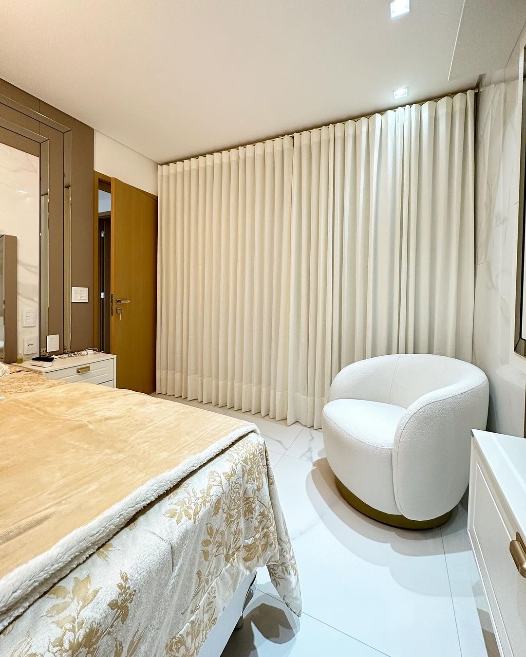 Cortinas plissadas bege em quarto moderno com poltrona branca