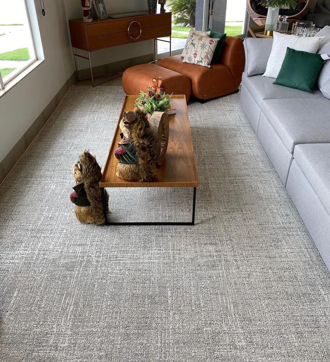 Tapete cinza amplo em sala com sofá e chaise de couro