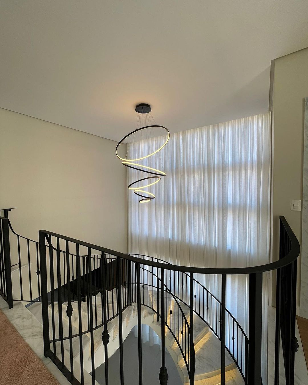 Cortinas brancas em escada com lustre espiral