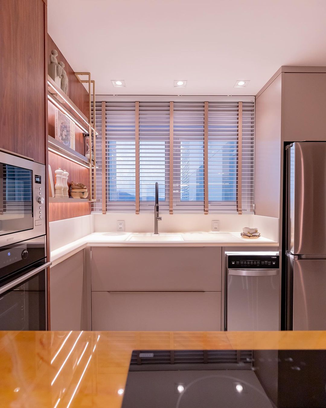 Persianas brancas horizontais com acabamento dourado em cozinha planejada