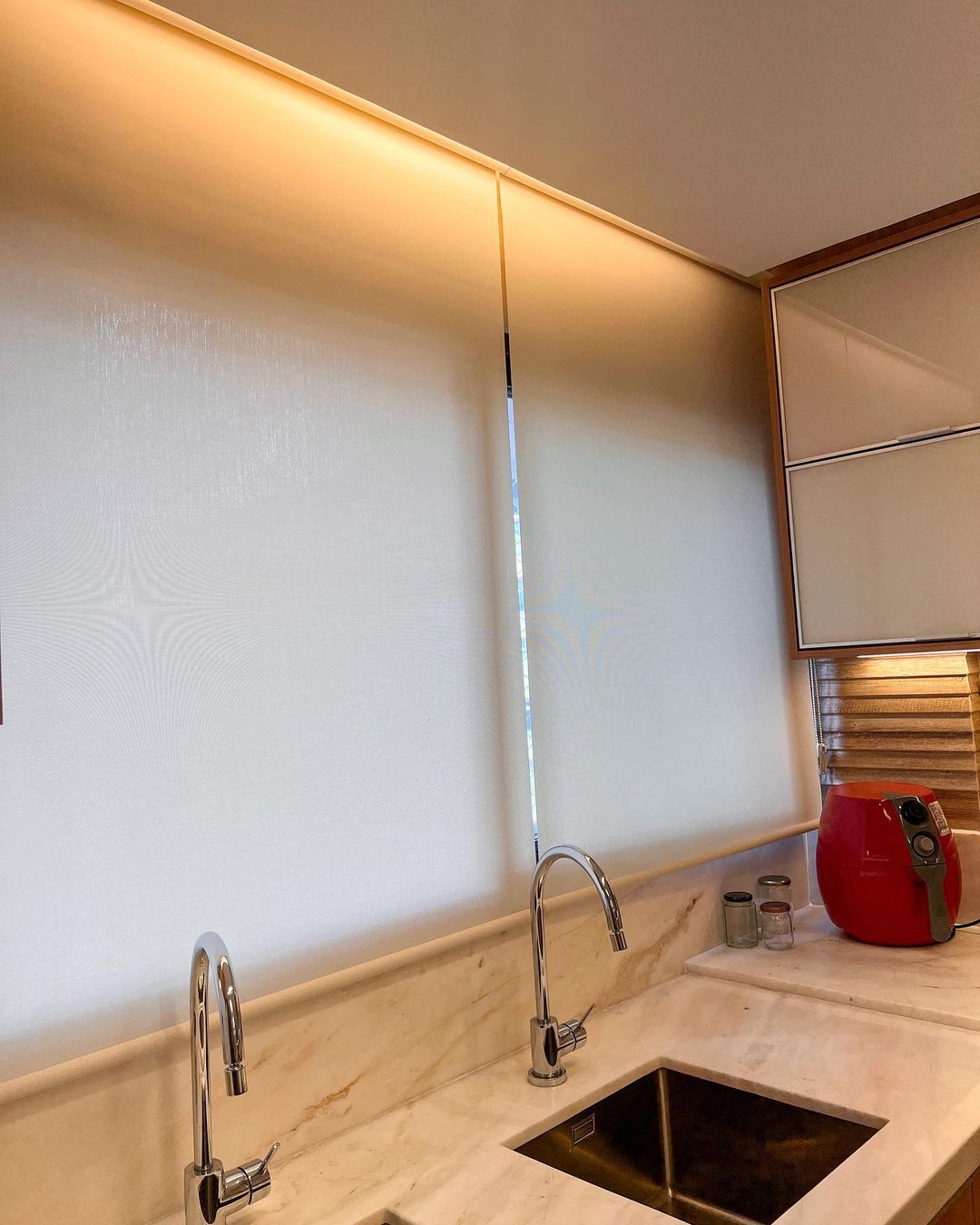 Cozinha elegante com persianas rolô brancas e bancada de mármore