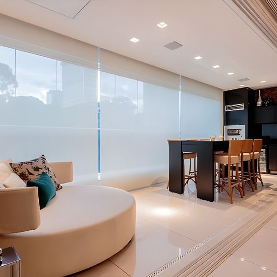 Sala integrada moderna com persianas rolô brancas do piso ao teto e sofá curvo