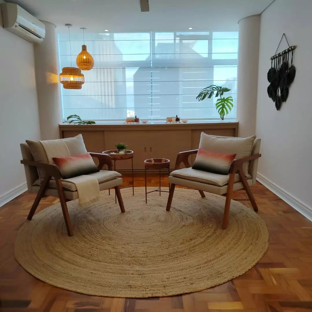 Sala de estar aconchegante com poltronas de madeira e persiana horizontal branca