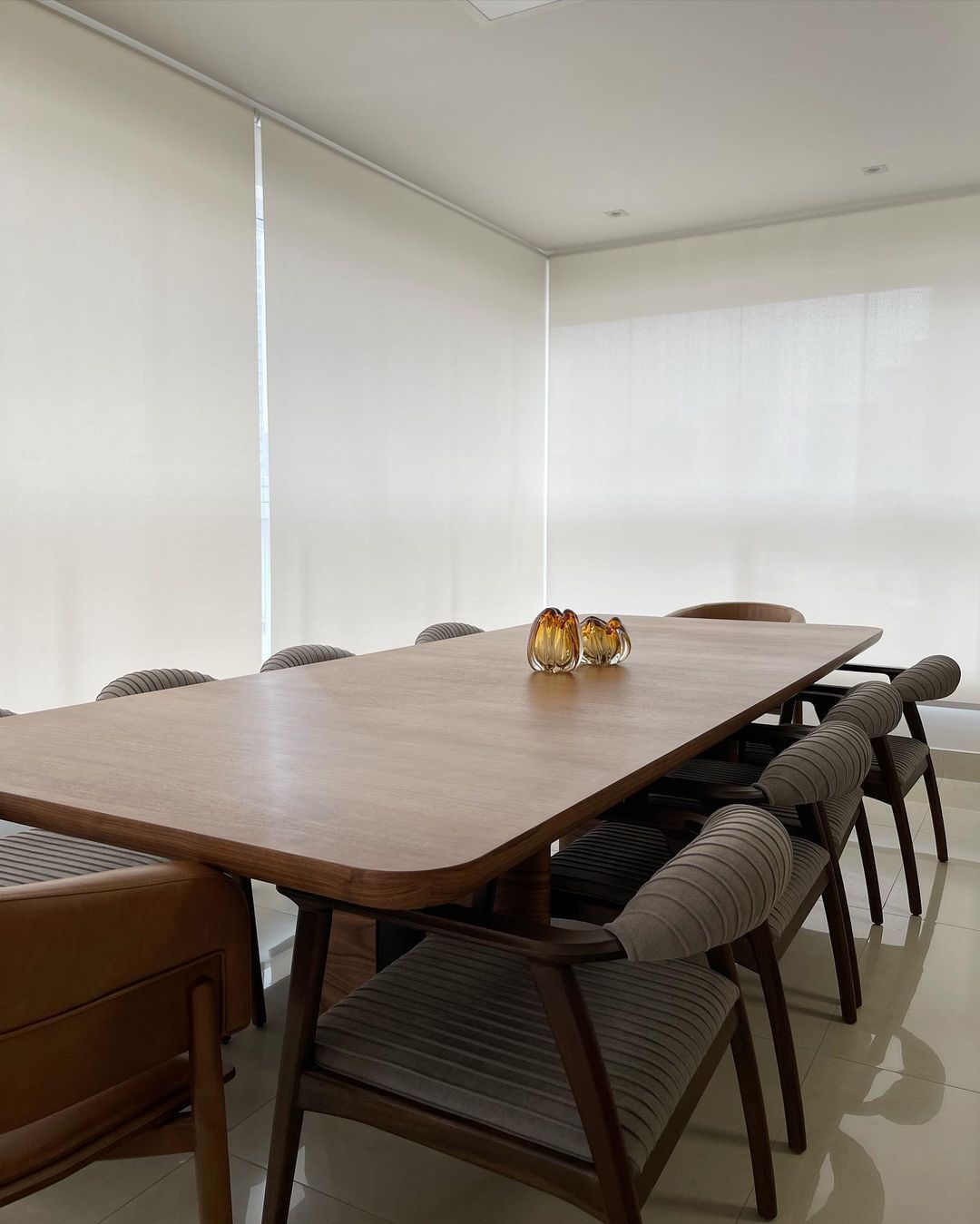 Sala de jantar elegante com persianas rolô brancas em janelas de canto